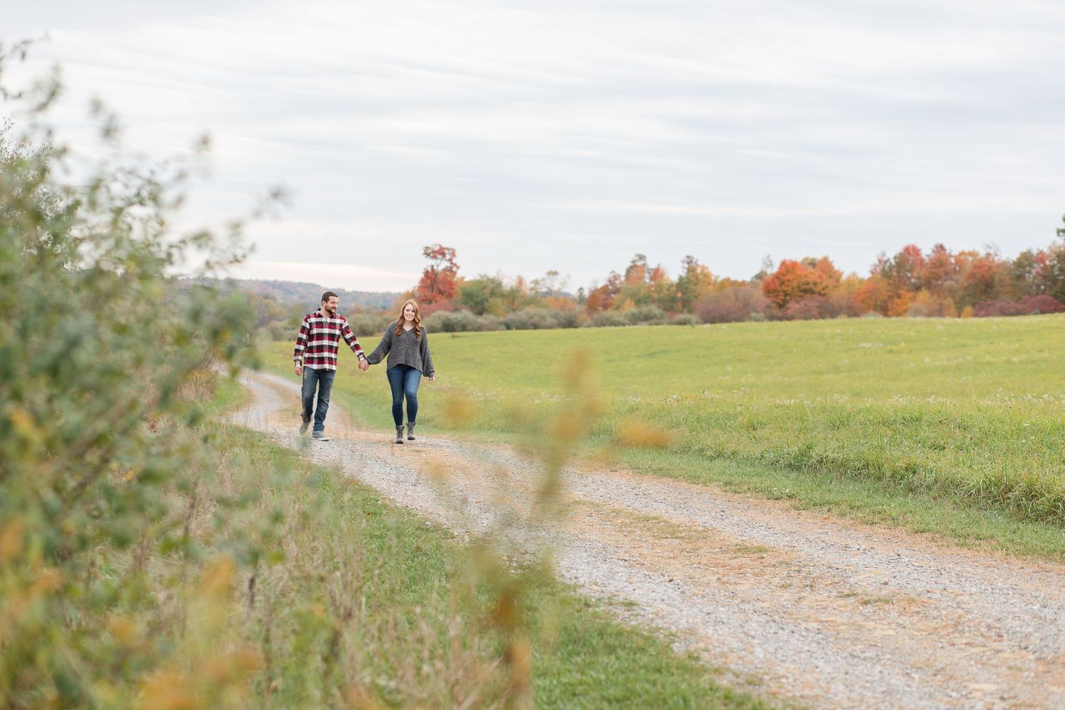 Scenic country path through autumn fields with distant figures walking.