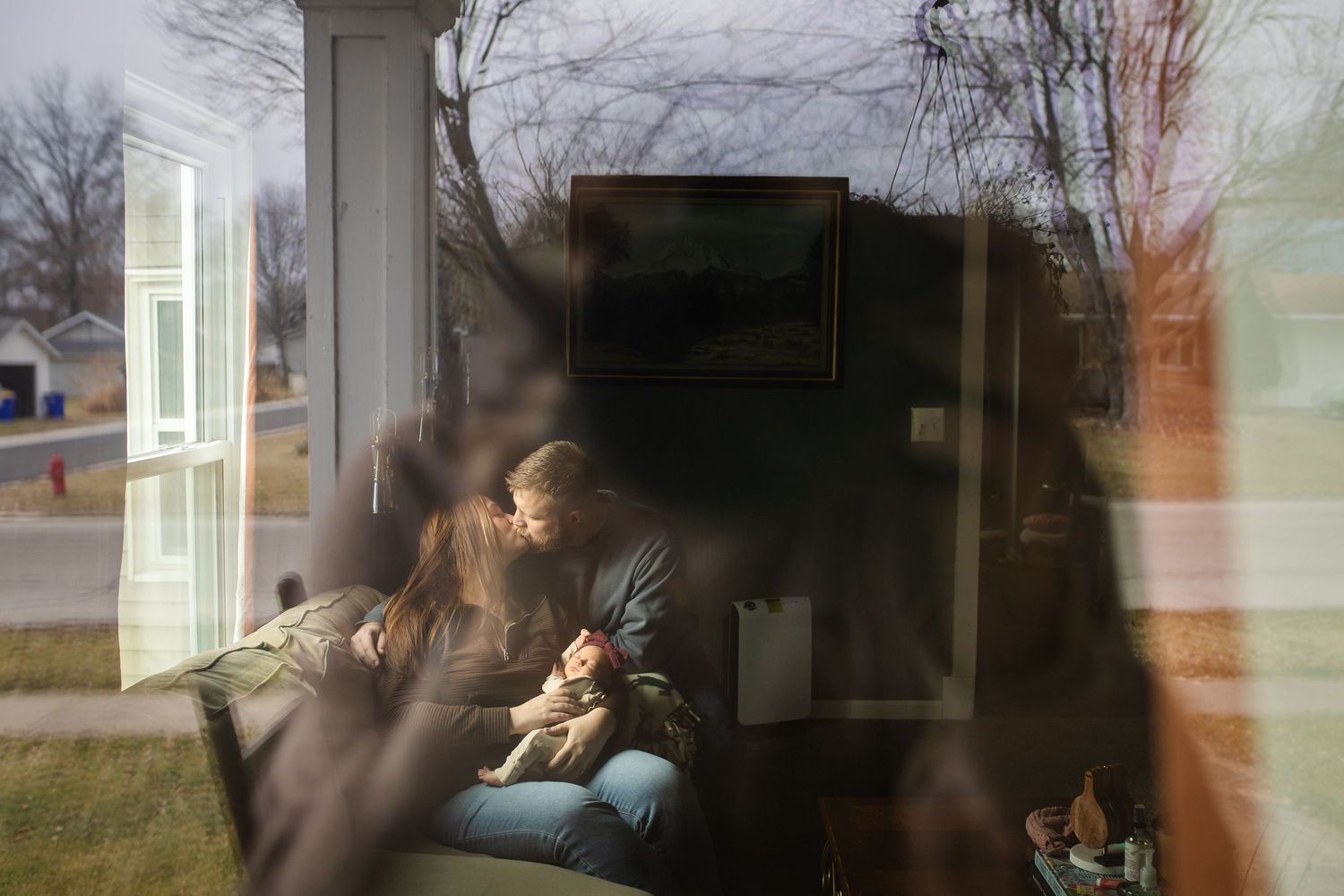 Family sharing tender moments with their newborn baby in a cozy living room setting.