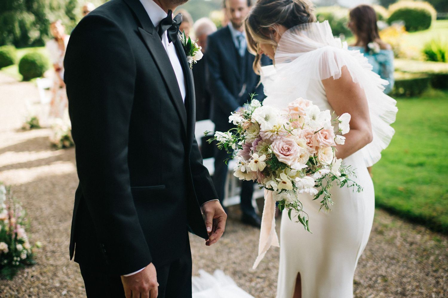 Wedding guests celebrate during an outdoor garden reception with champagne toasts and floral decorations.