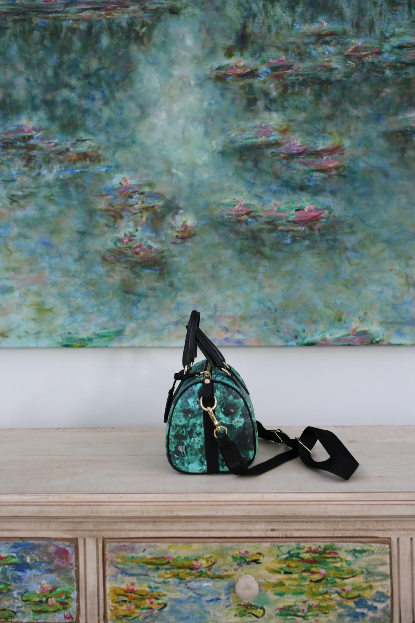 Modern living room with Monet-style water lilies artwork displayed above white chairs and organic wooden coffee table.