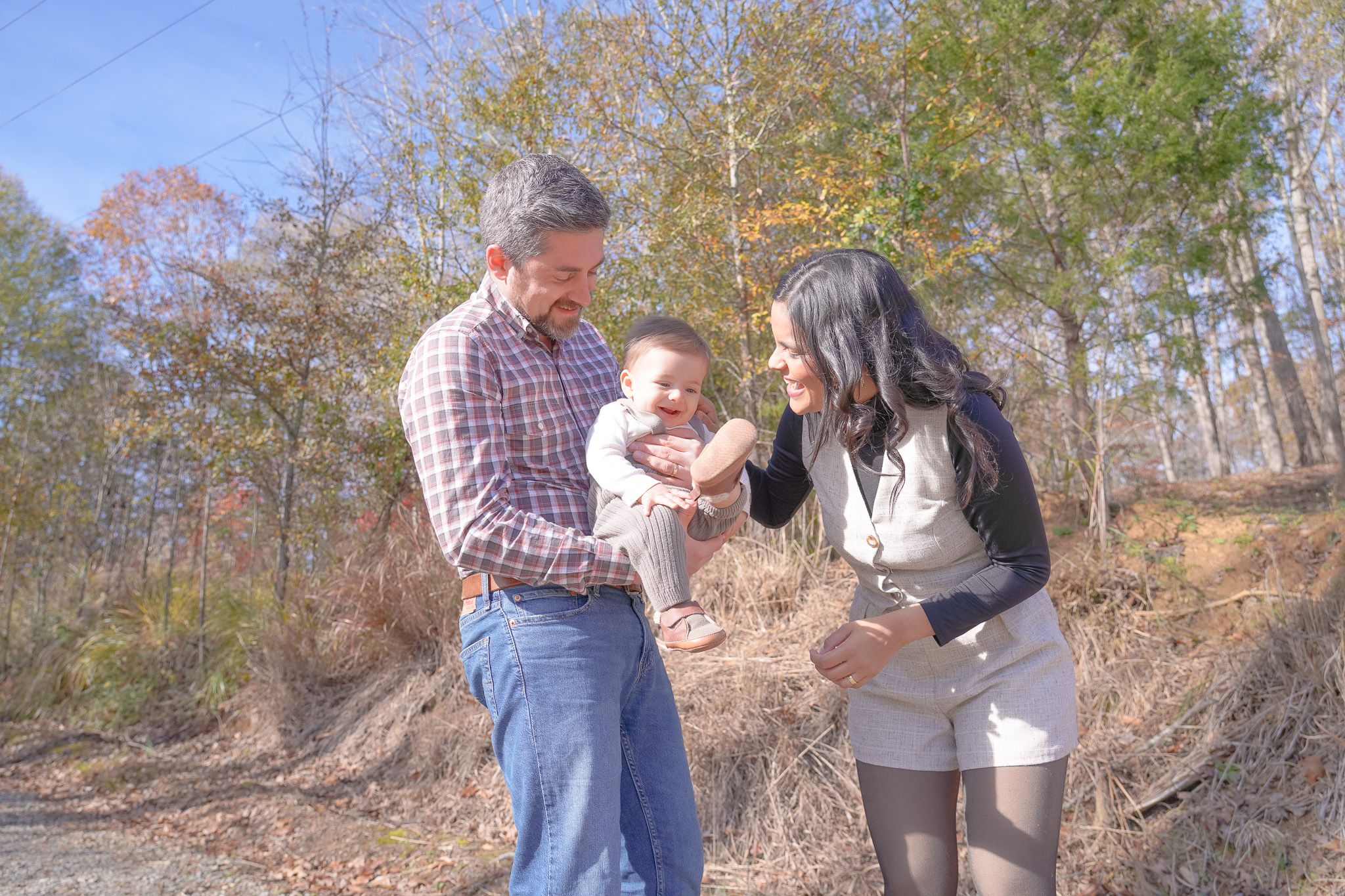 A happy family shares joyful moments together in an autumn forest setting during a sunny day. Lincolnton NC Family Photography
