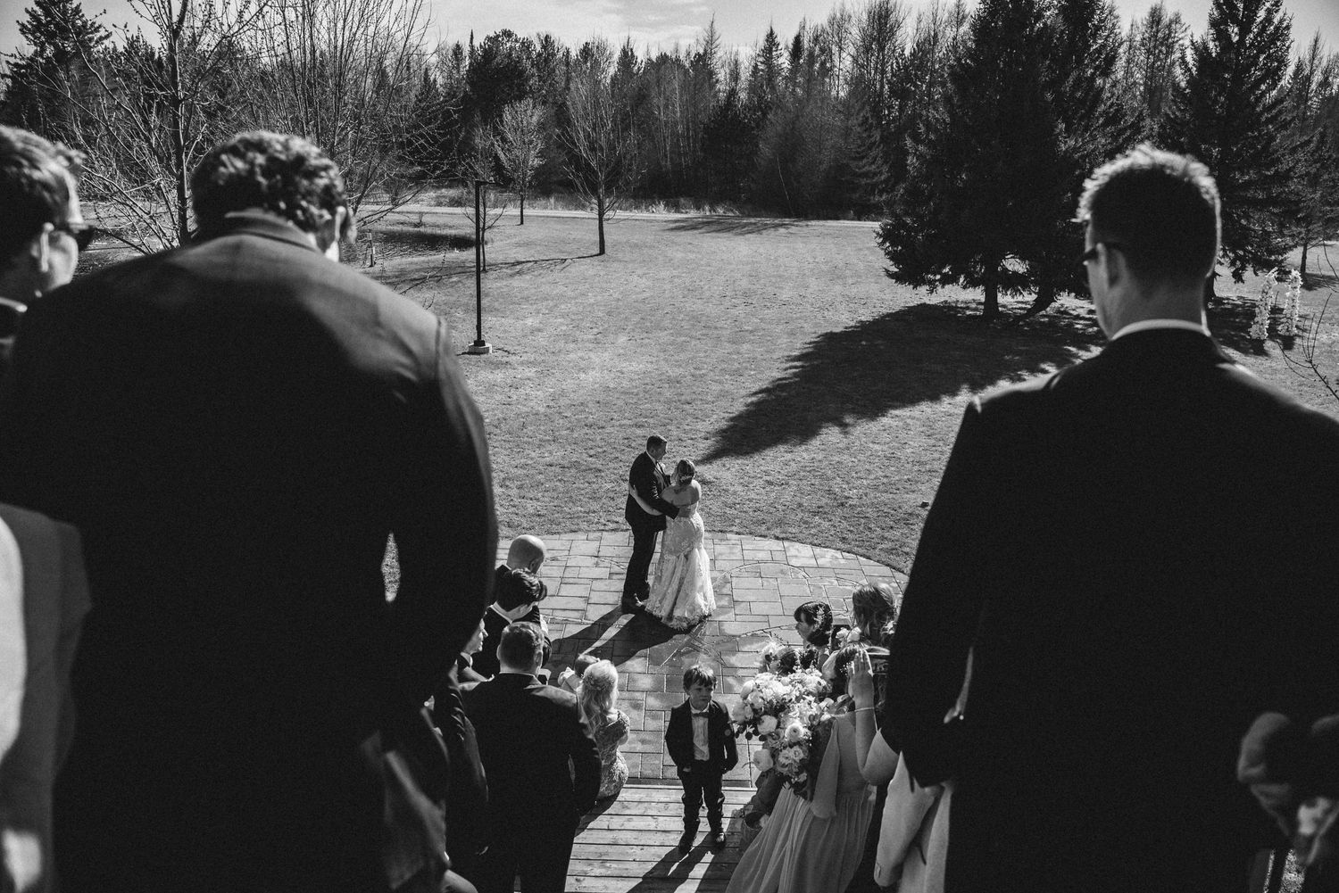 Rustic barn wedding guests dance on wooden floors with warm lighting and decorative string lights overhead.