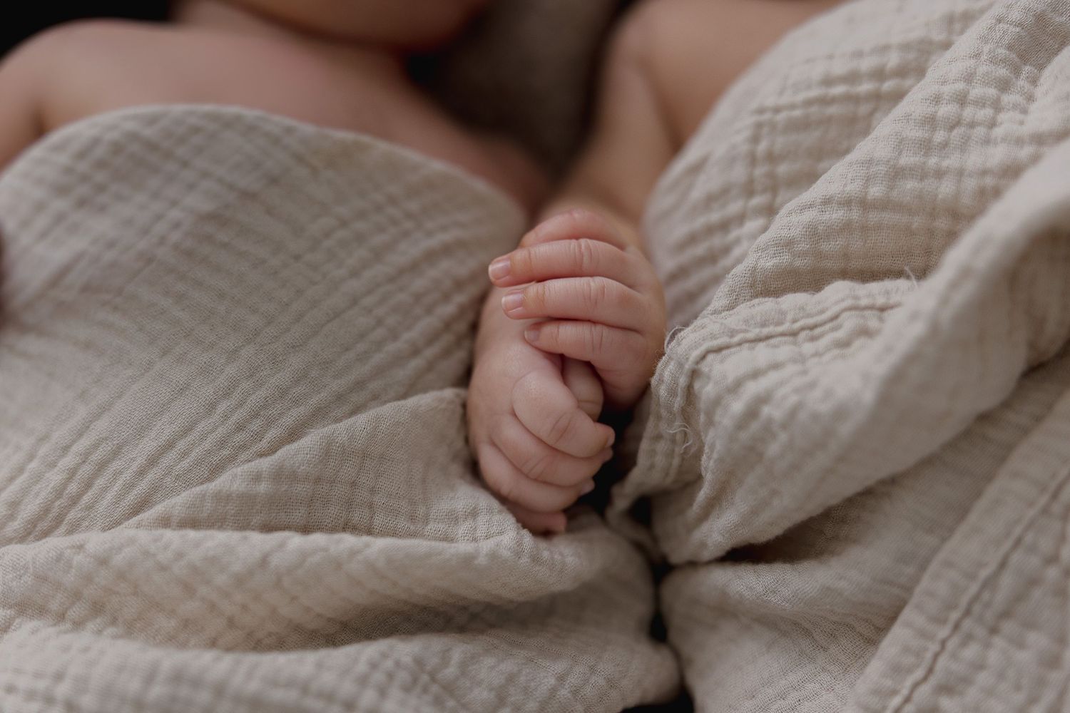 Close-up view of hands gently holding and caressing soft beige knitted fabric or blanket texture.