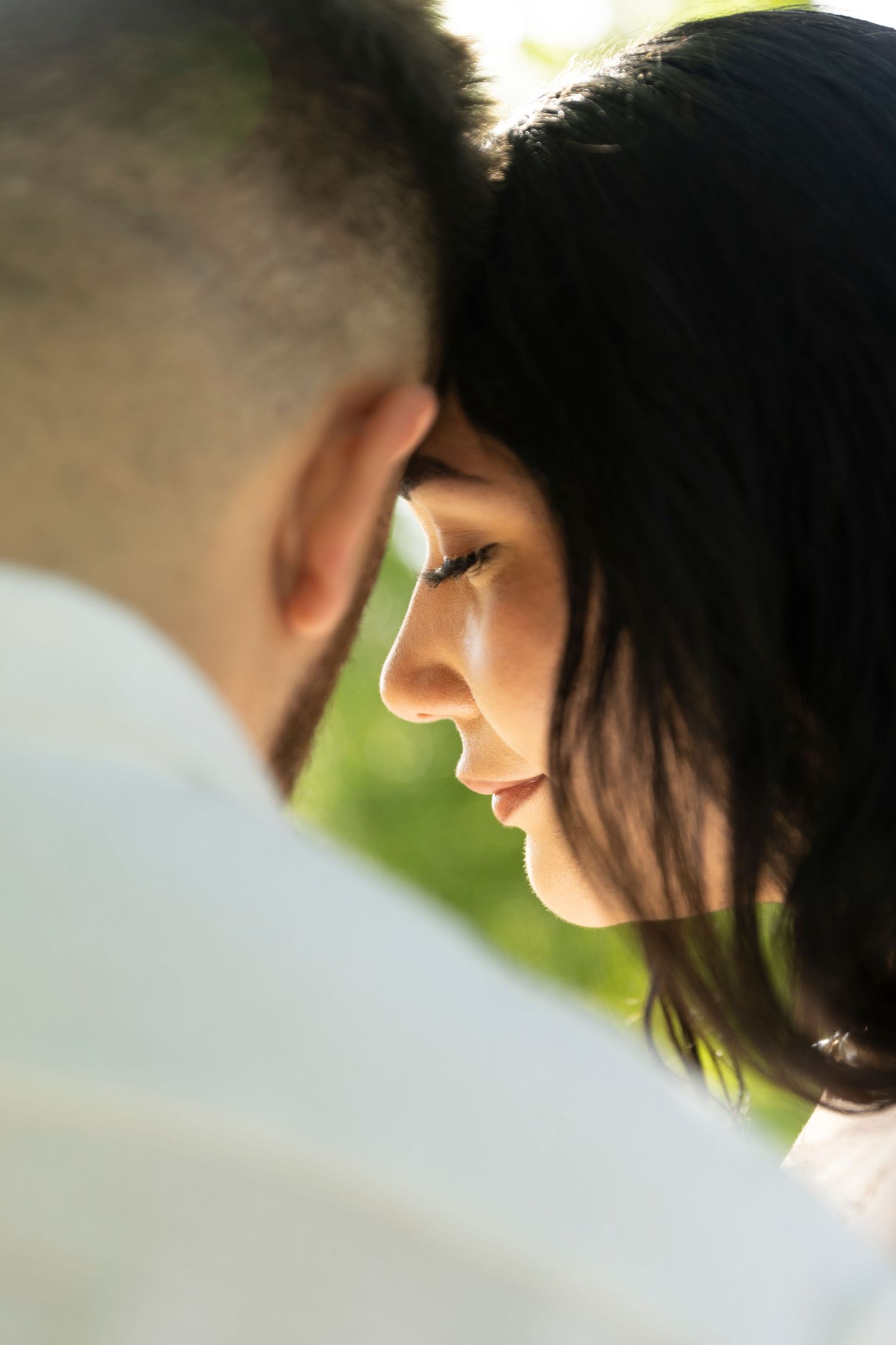 A romantic close-up side profile shot of a couple in soft sunlight creating an intimate moment.