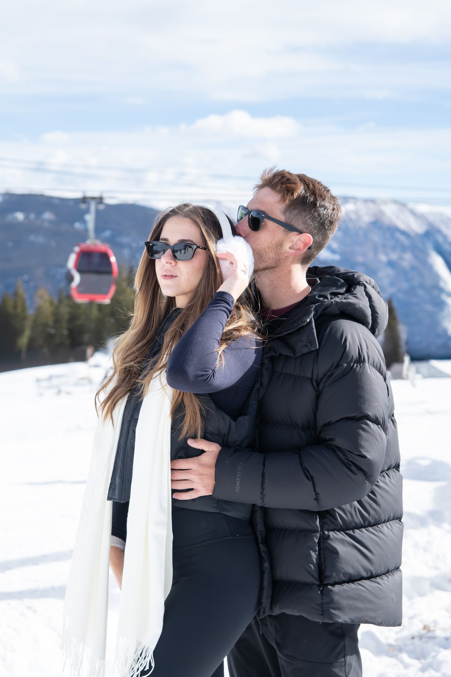 Chic couple walks together during engagement session at the top of Aspen mountain in the snow with winter scenery.