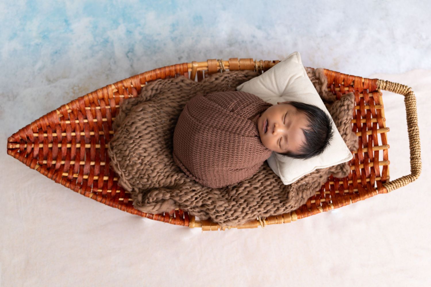 Someone wearing a cozy sweater lies curled up asleep on an orange textured sofa in a relaxing pose.
