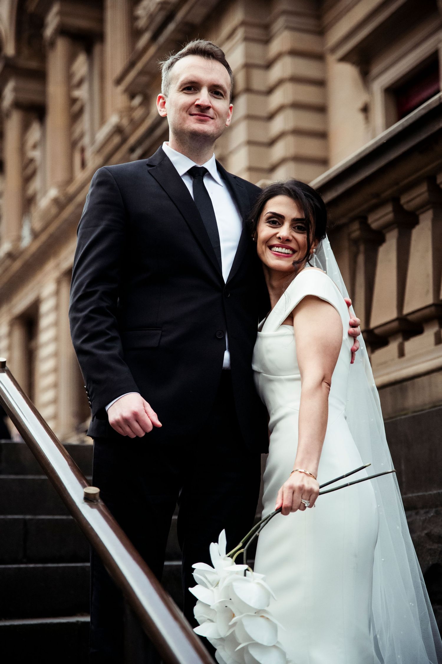 A bride and groom pose together on stone steps outside a historic building in a series of candid wedding photos.