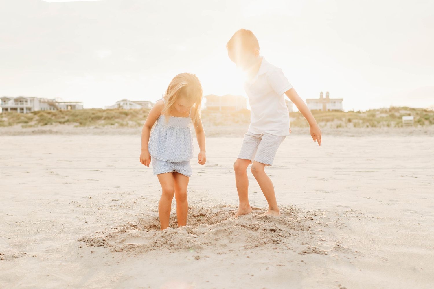 People wearing light colored clothing walk on a sandy beach at sunset creating a peaceful coastal scene.