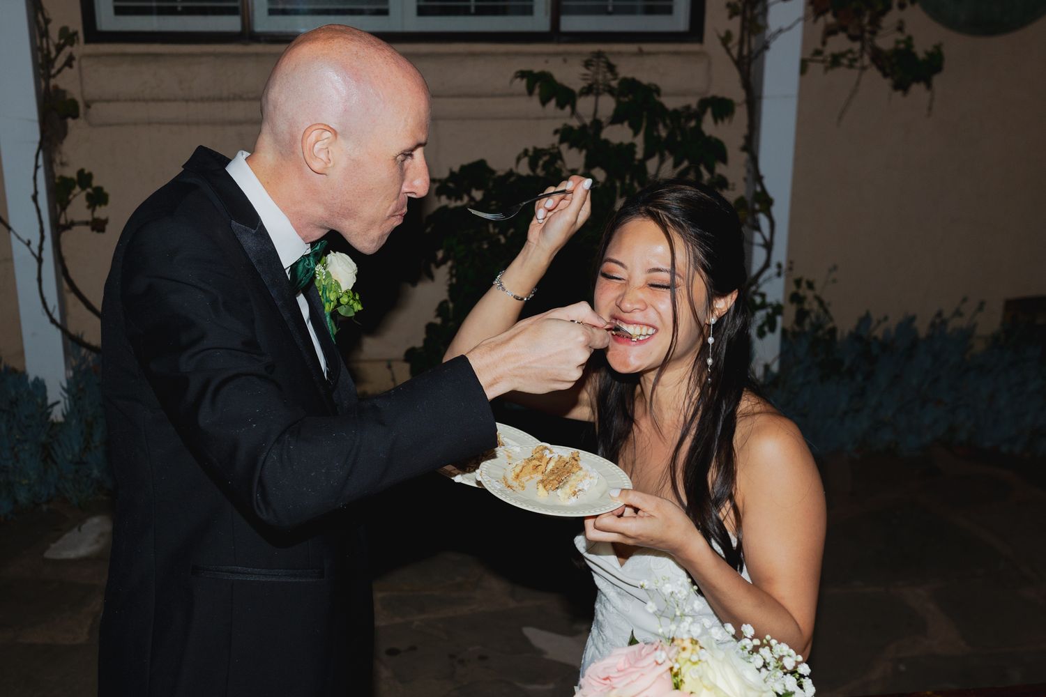 Playful cake cutting moment at wedding reception indoors.