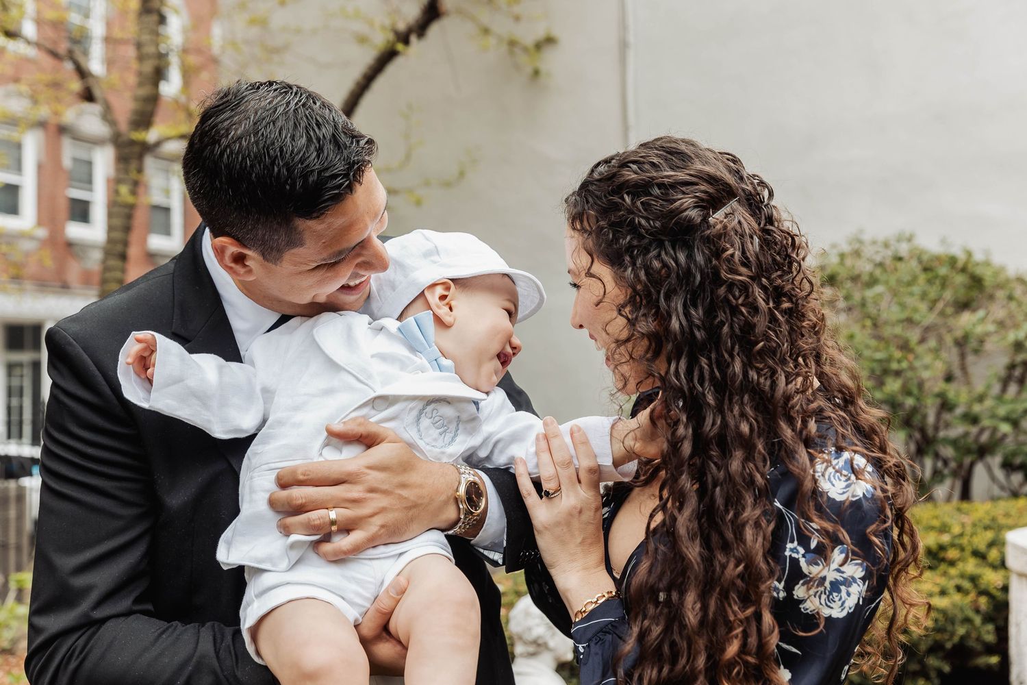 A sweet family moment outdoors with a baby in white clothing.