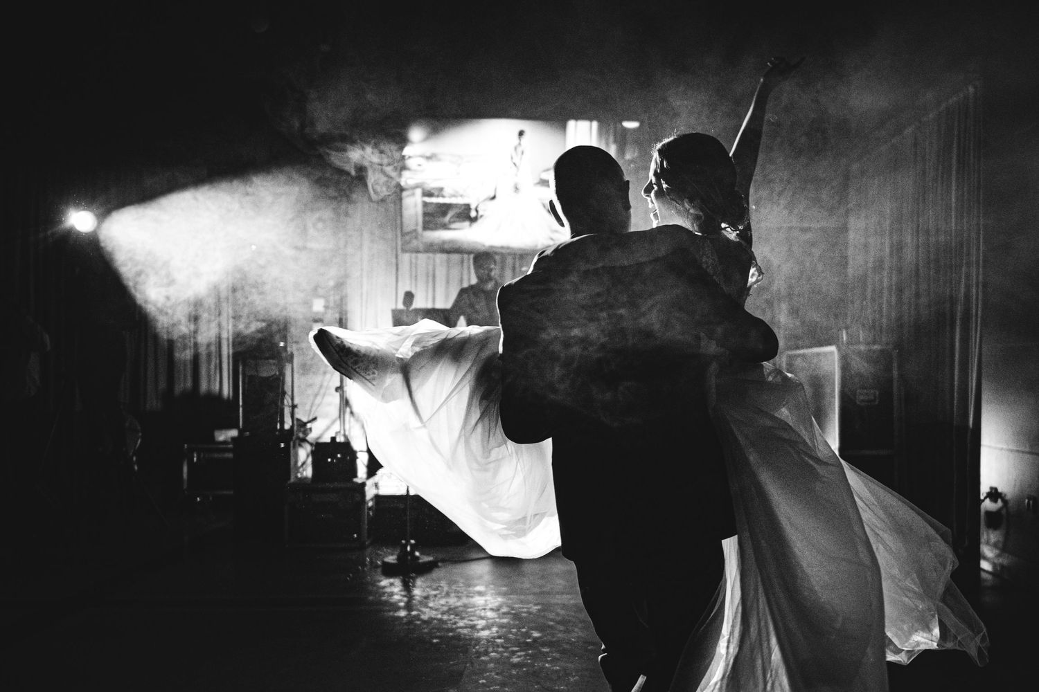Una pareja de novios baila juntos con poca luz y espectaculares efectos de luz y humo. Mejores fotógrafos de boda en Asturias. Juan Llavio.