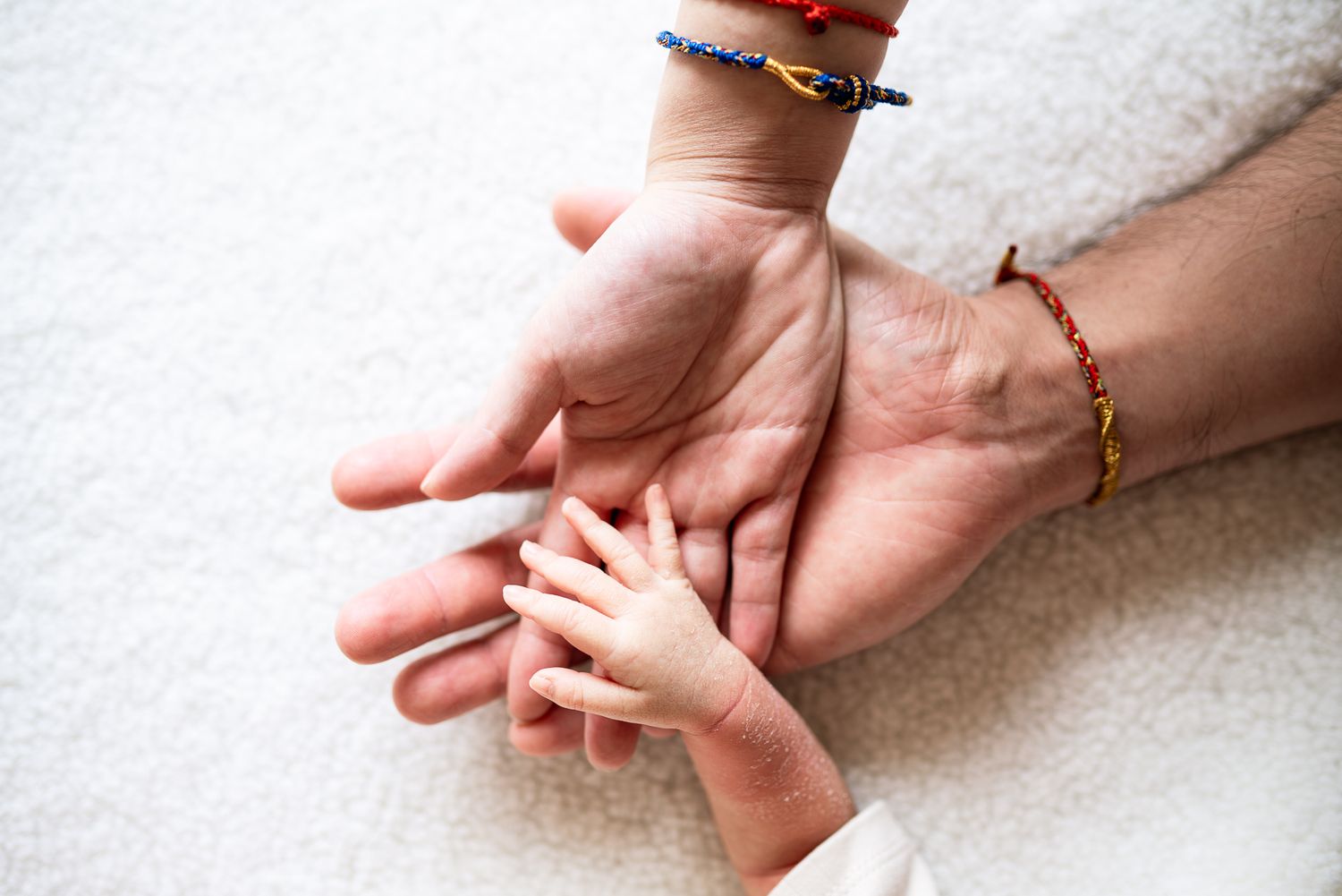 Close up view of parents' hands holding a small delicate newborn hand taken by a Melbourne newborn photographer Pei A Photography.