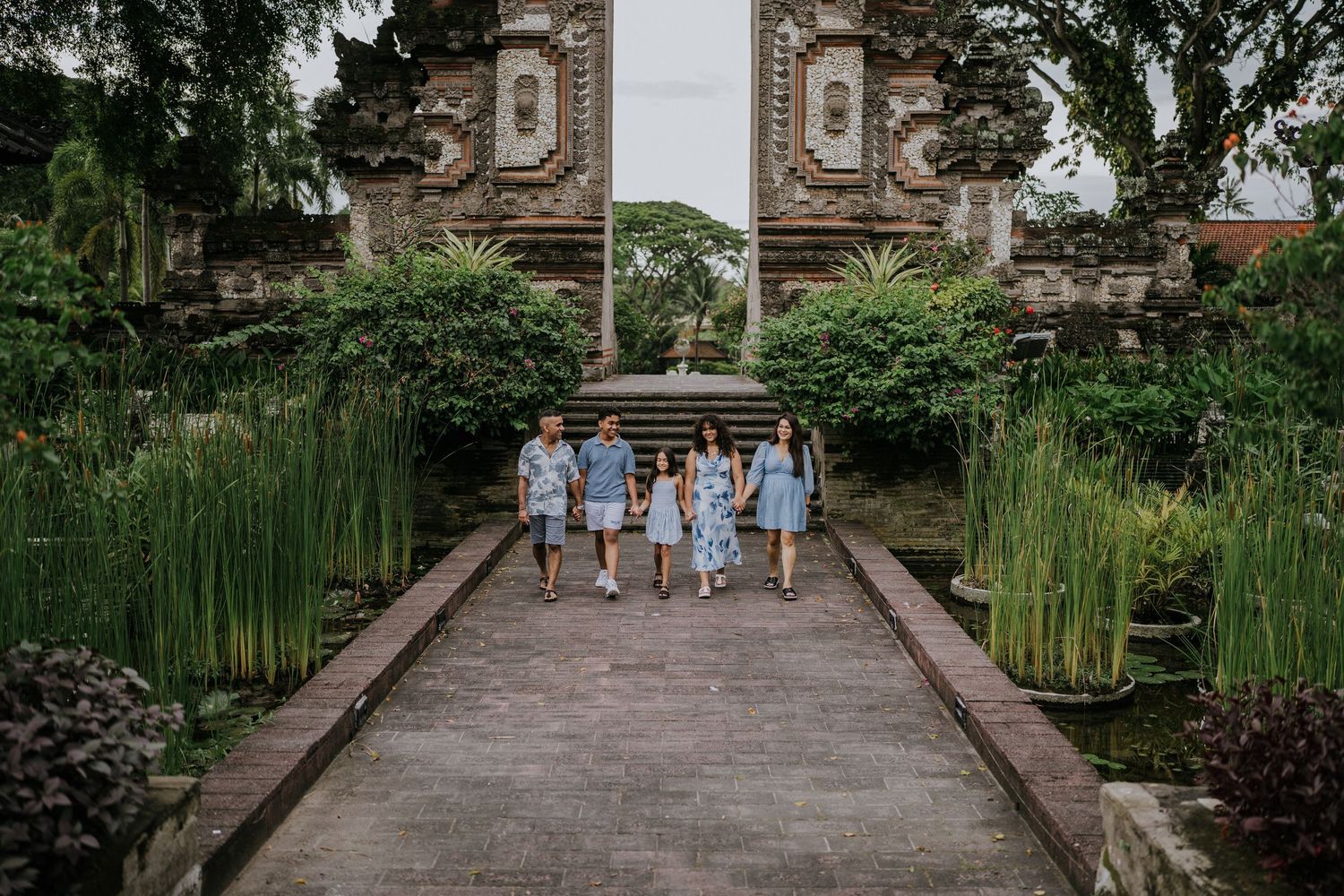 Couple walking along a green garden pathway surrounded by tropical plants.