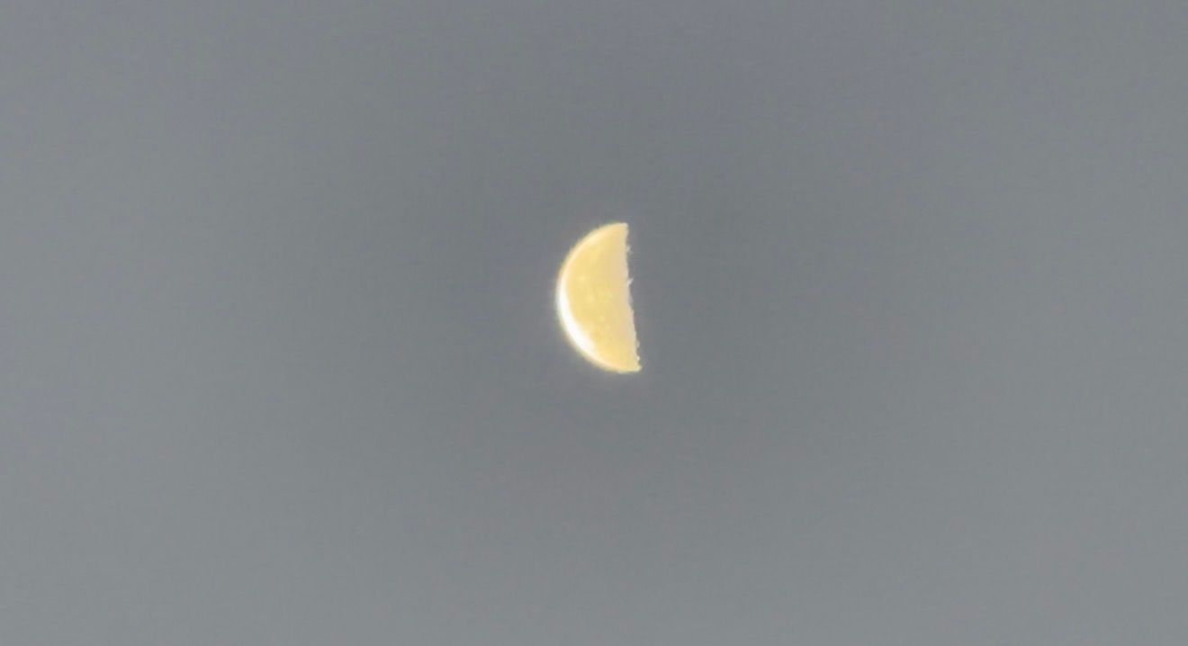 A sequence of five images showing different phases of the moon in a grey cloudy sky.