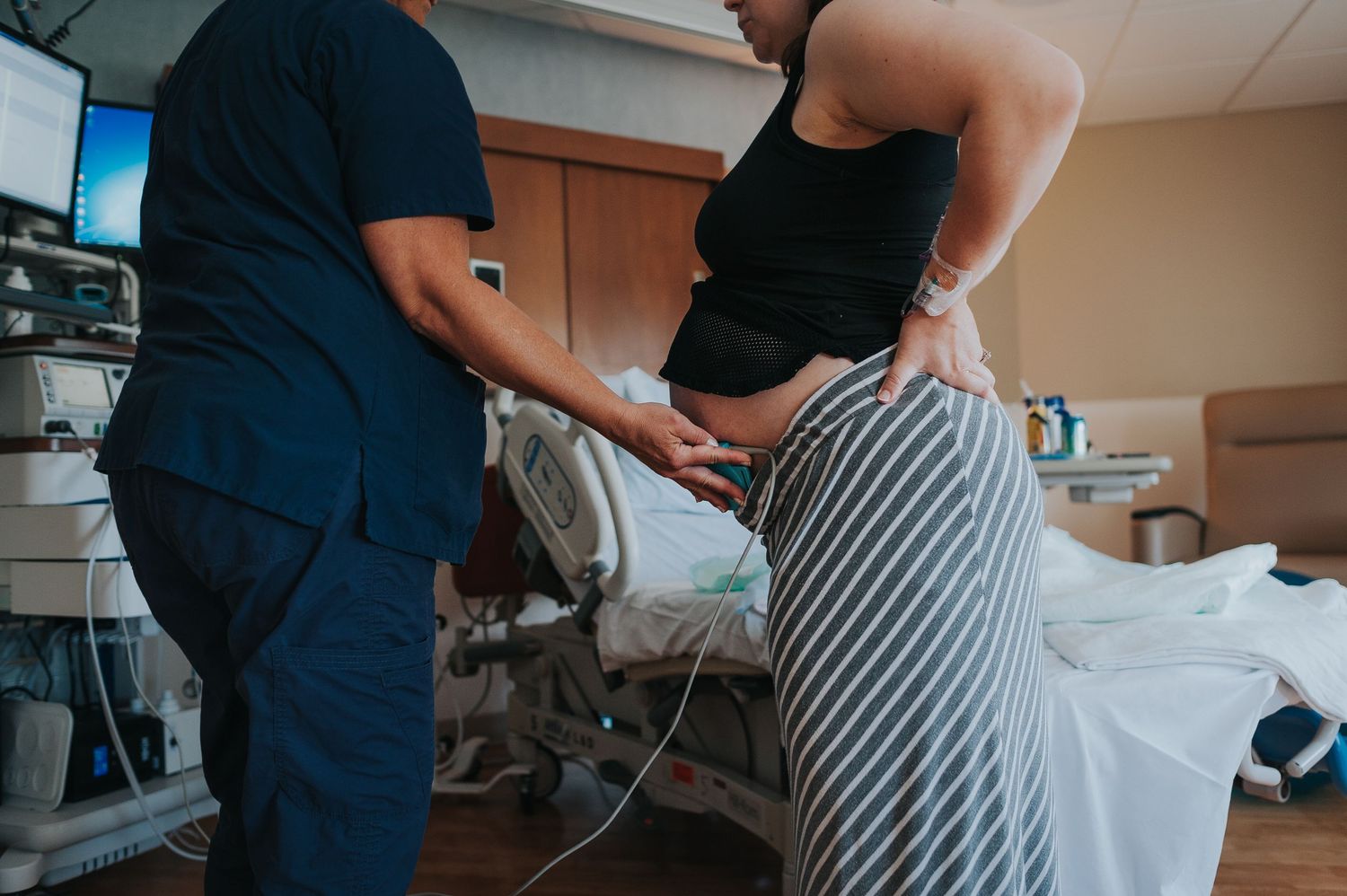 A woman in labor in Lincoln NE stands next to her nurse, who is placing a monitor on her belly to listen to her baby's heartrate