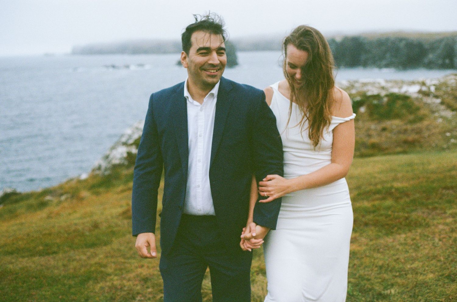 35 mm film photo of bride and groom walking along rocky shoreline in Squamish, BC