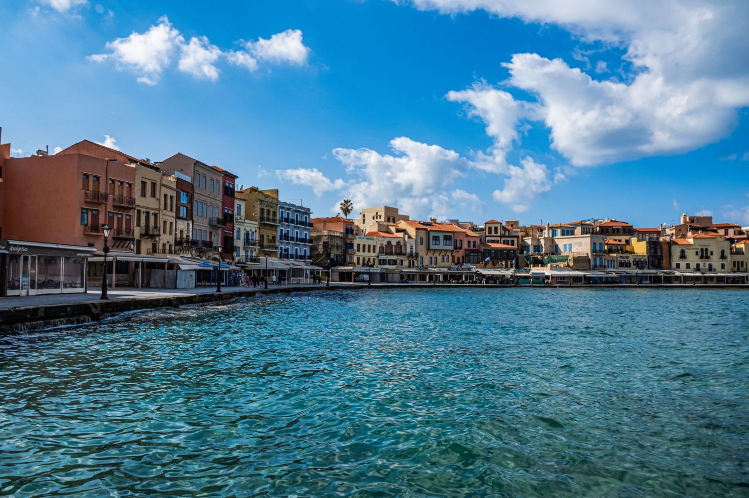 A panoramic view of Venice's waterfront buildings and turquoise canals under a bright blue sky with white clouds.