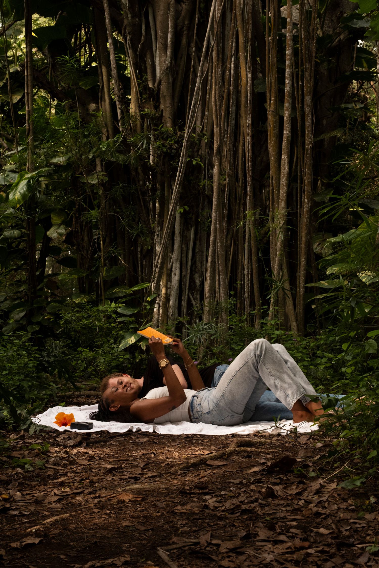 Couple relaxing on a blanket in a lush tropical forest during Oahu North Shore couples photo session.