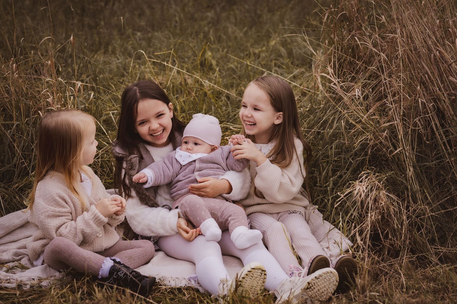Family members in matching pink outfits sitting together outdoors during golden hour photography session.