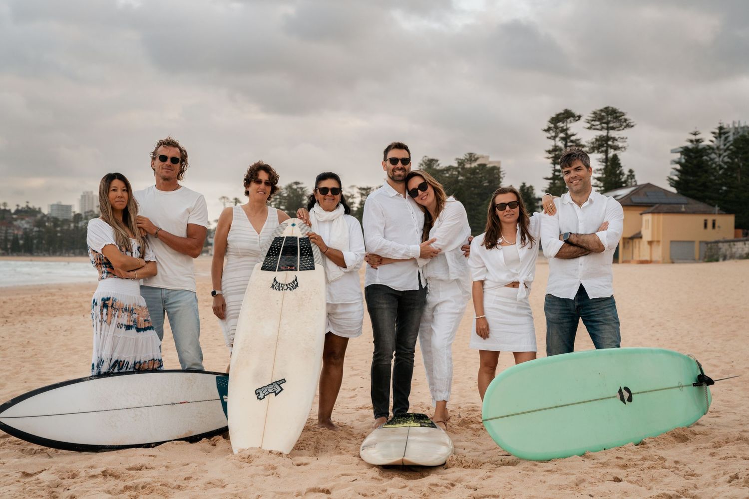 Beach group photo session with surfboards arranged on sandy shoreline.
