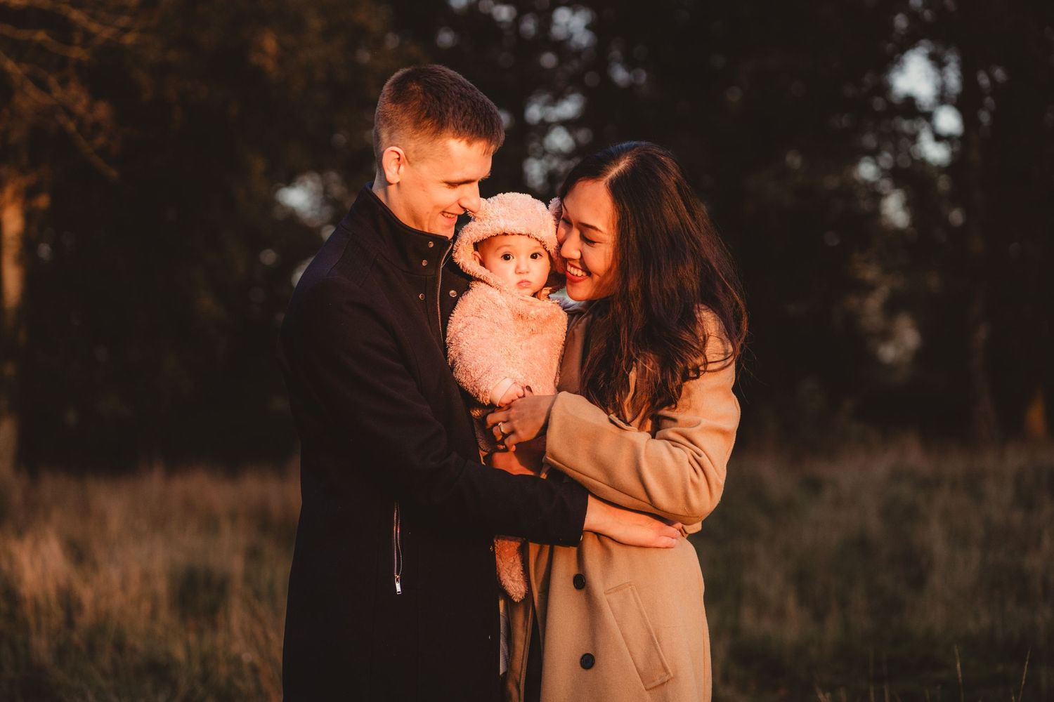 Young family cuddling their baby during a golden hour photoshoot in Hertfordshire. Warm sunset light creates a soft, natural glow.
