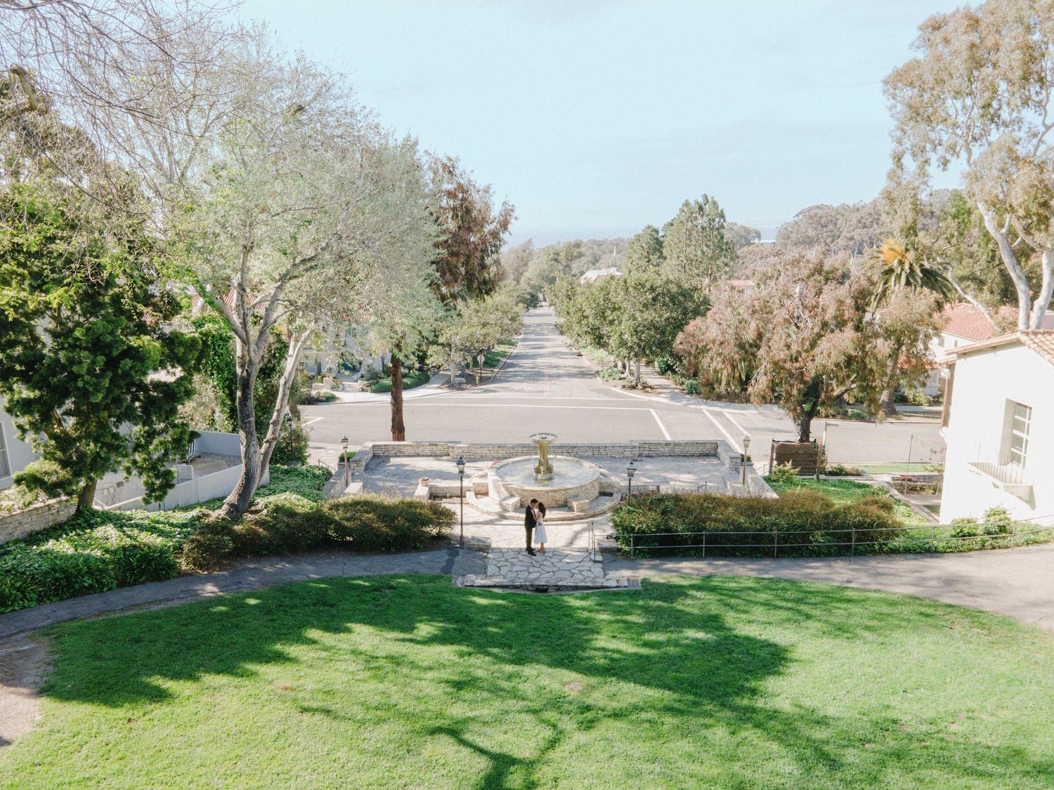 Aerial perspective of a symmetrical garden path lined with trees on a sunny day.