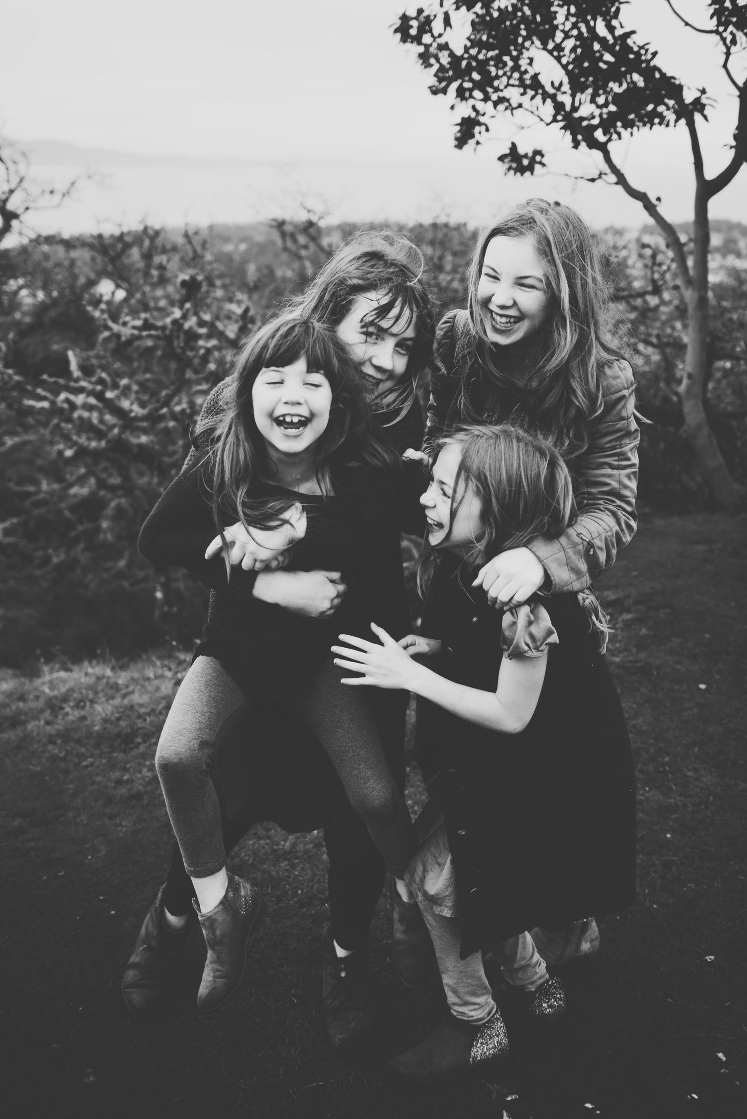 A joyful group sharing laughter and embraces outdoors in black and white photography.