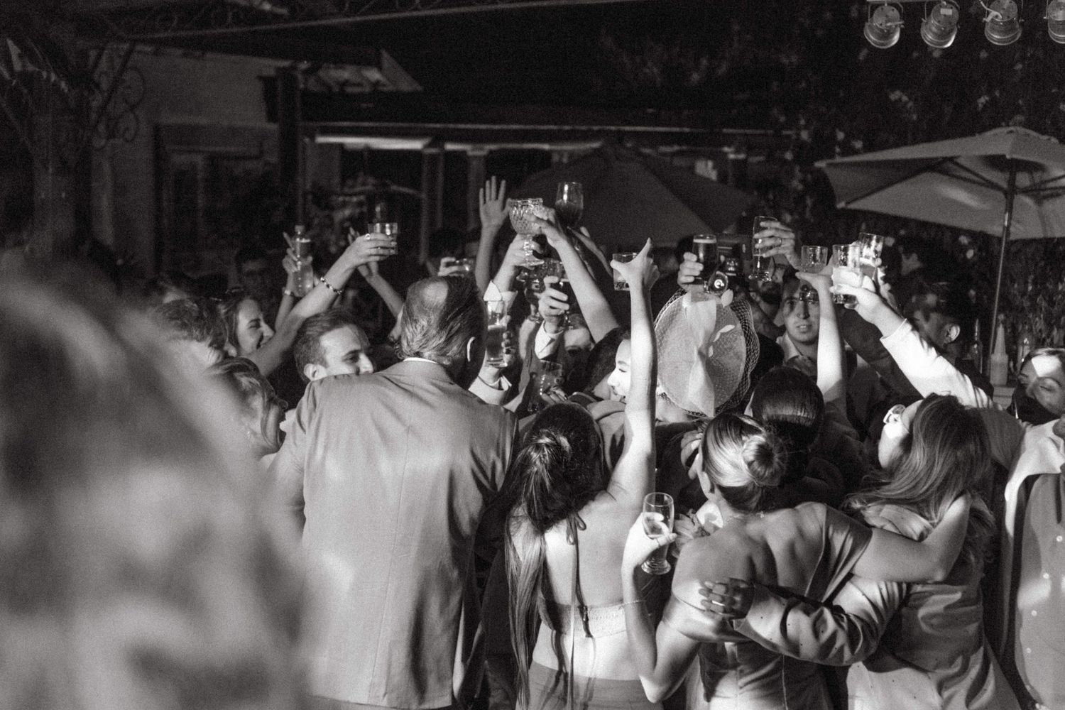 A crowded dance floor with people dancing and raising their hands at a celebration.