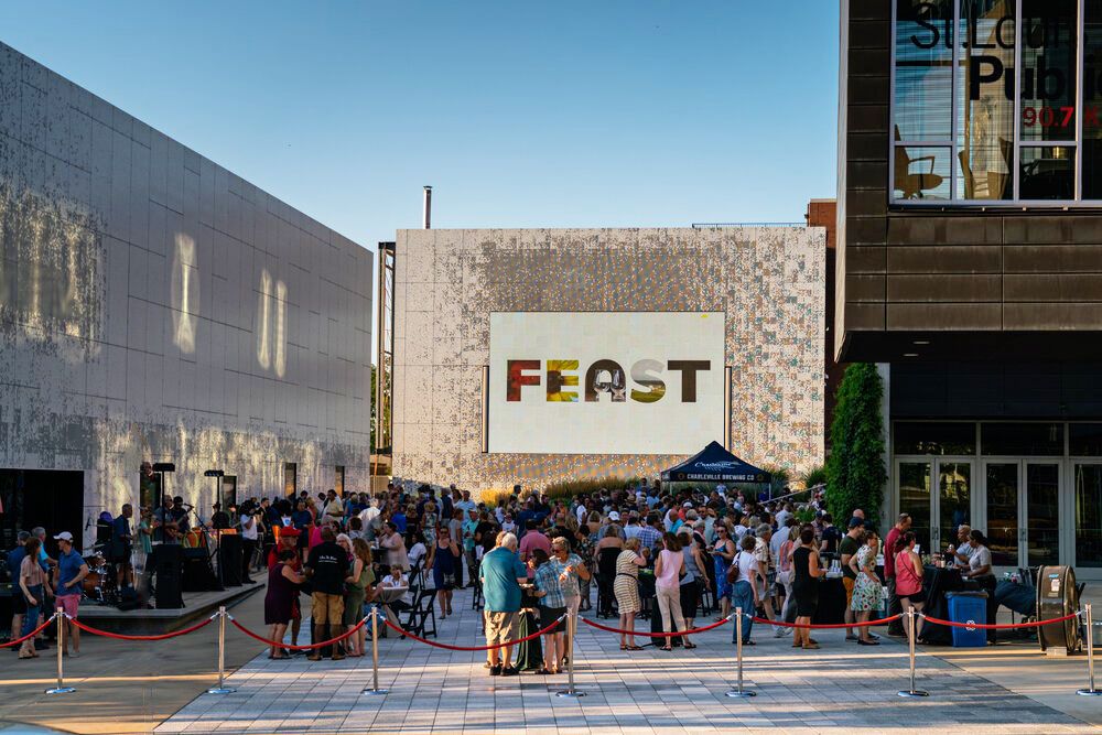 A crowd gathers outside FEAST restaurant on a sunny day.