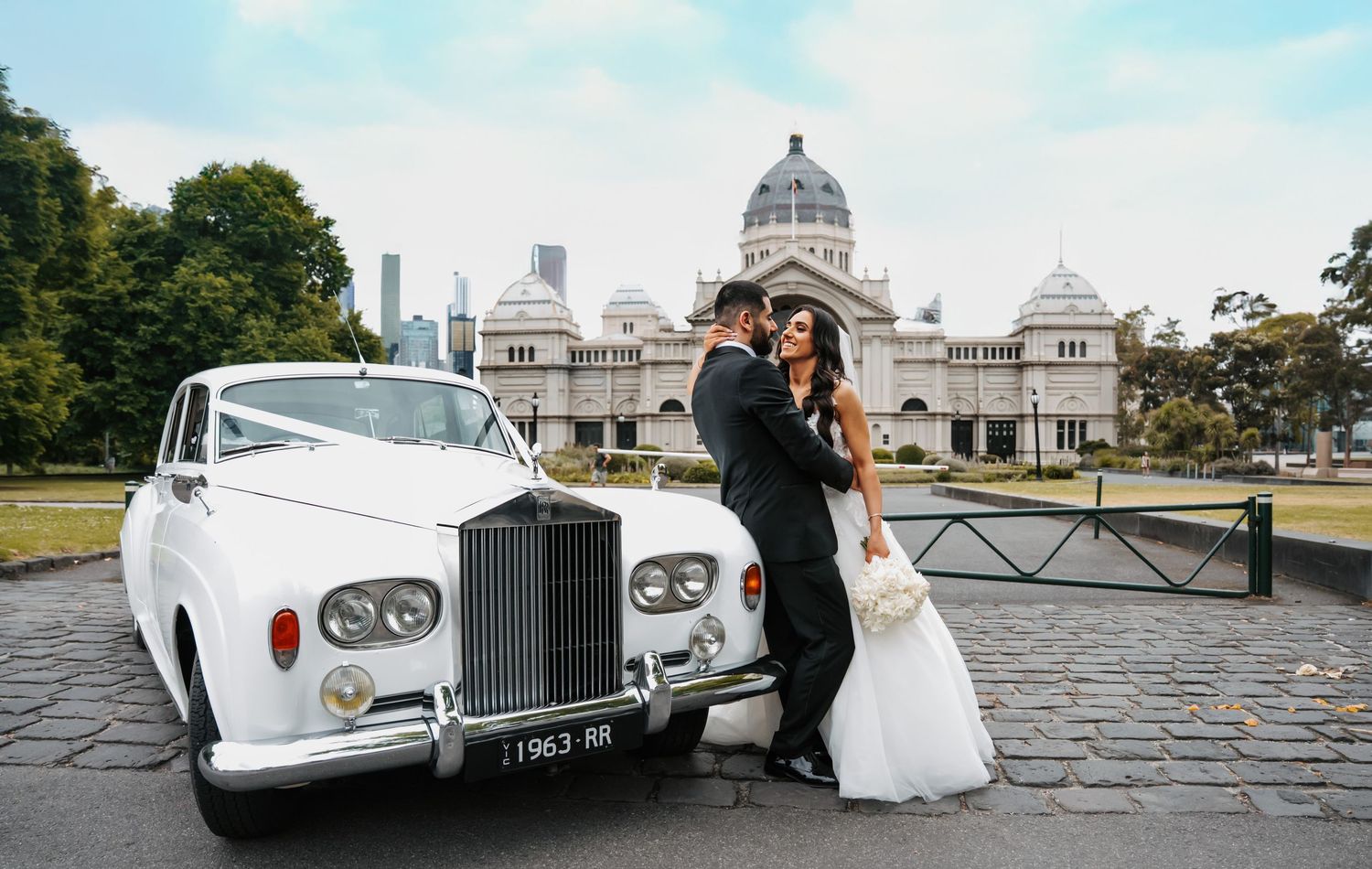 Classic white Rolls Royce parked in front of the Royal Exhibition Building in Melbourne for a wedding photoshoot.