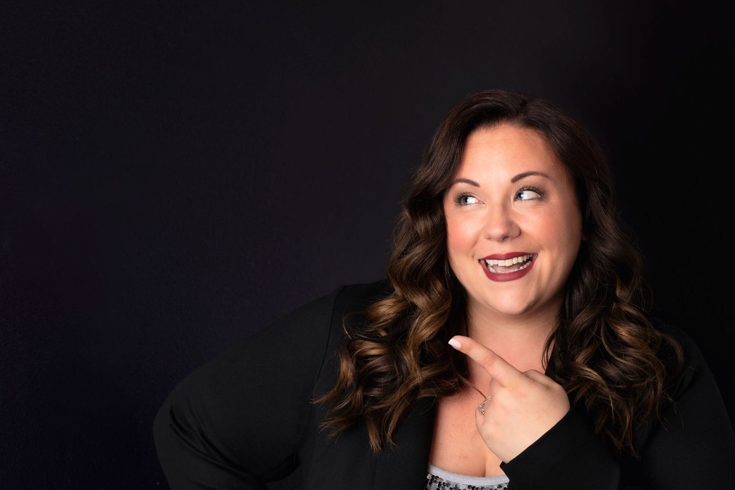Professional studio portrait against dark background with dramatic lighting.