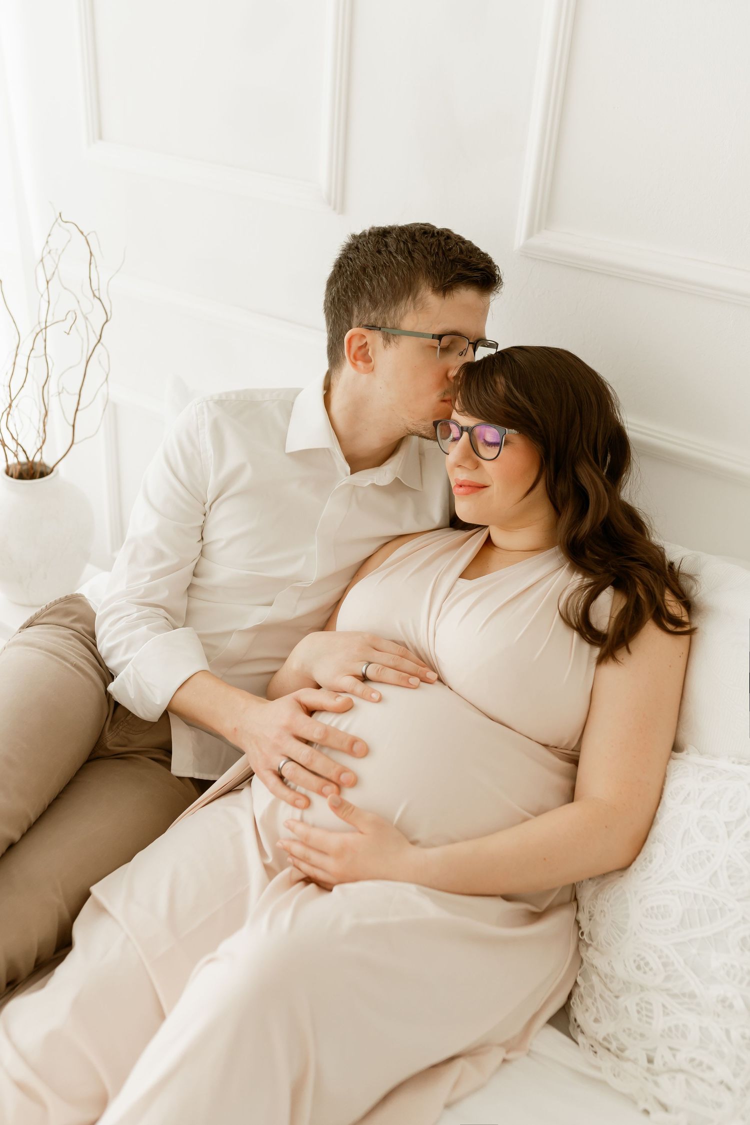 Intimate maternity photo of expectant couple sharing tender moment on couch.