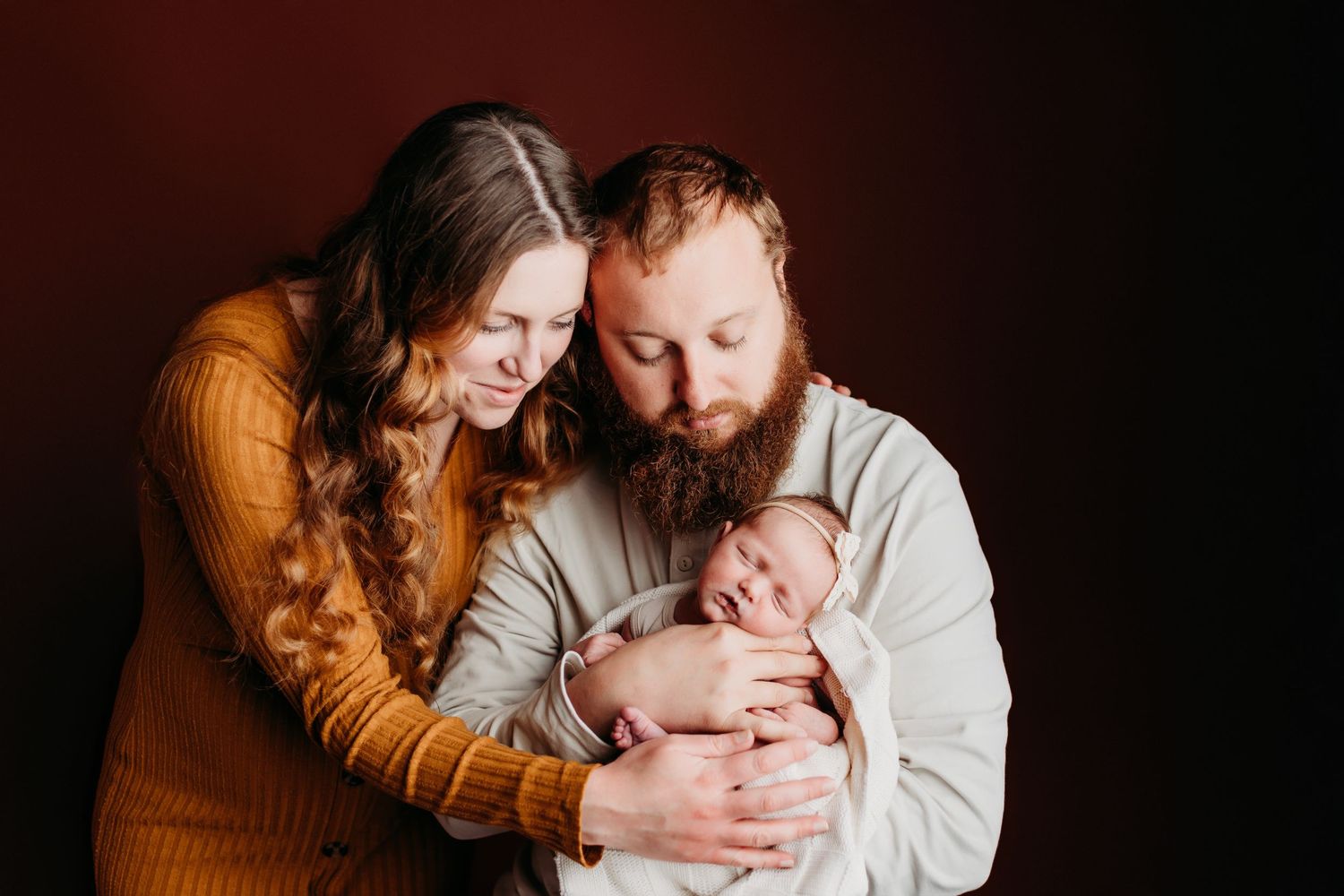 Family portrait in moody lighting with couple holding their newborn.