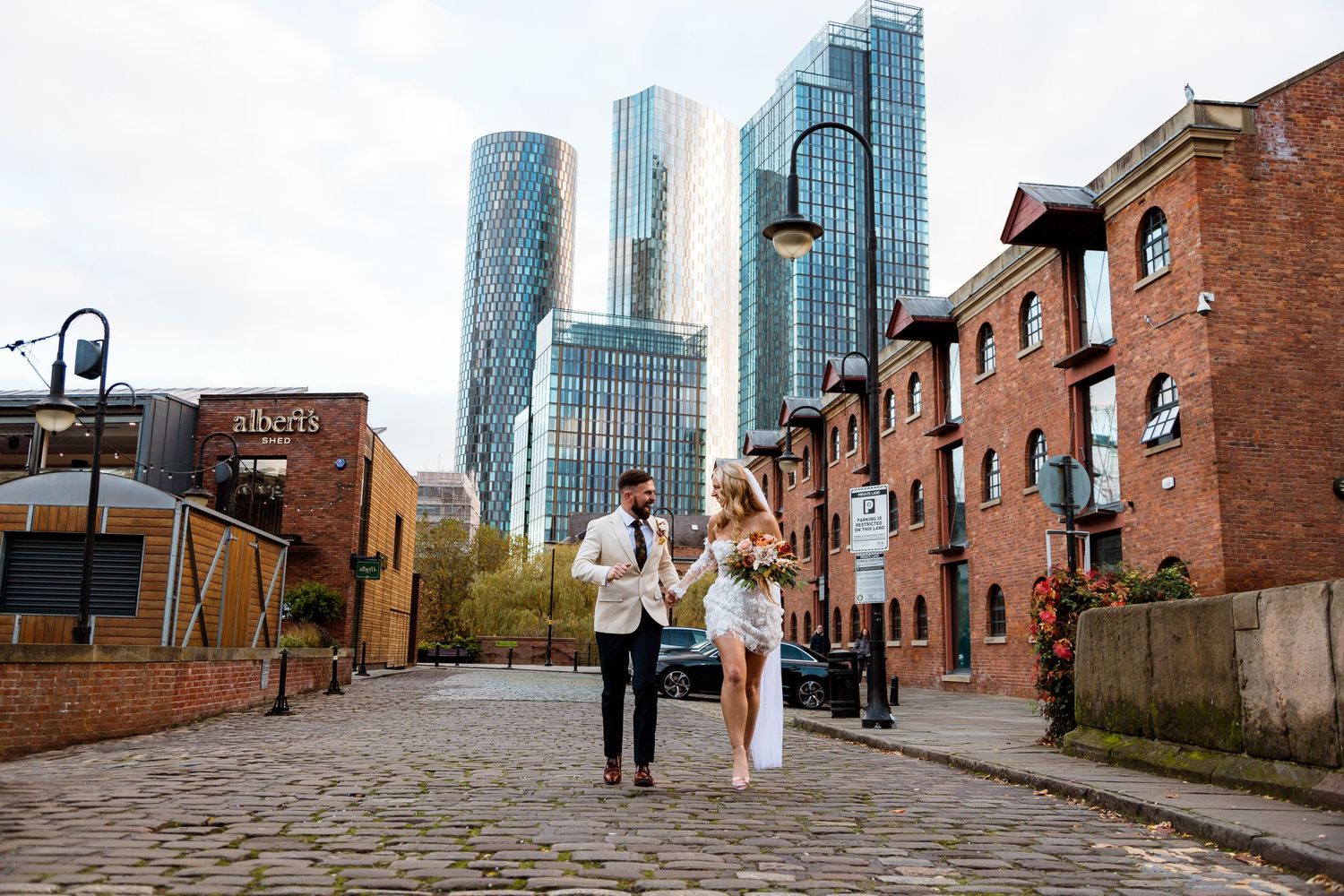Urban wedding photography session along historic brick buildings with modern skyscrapers in the background.