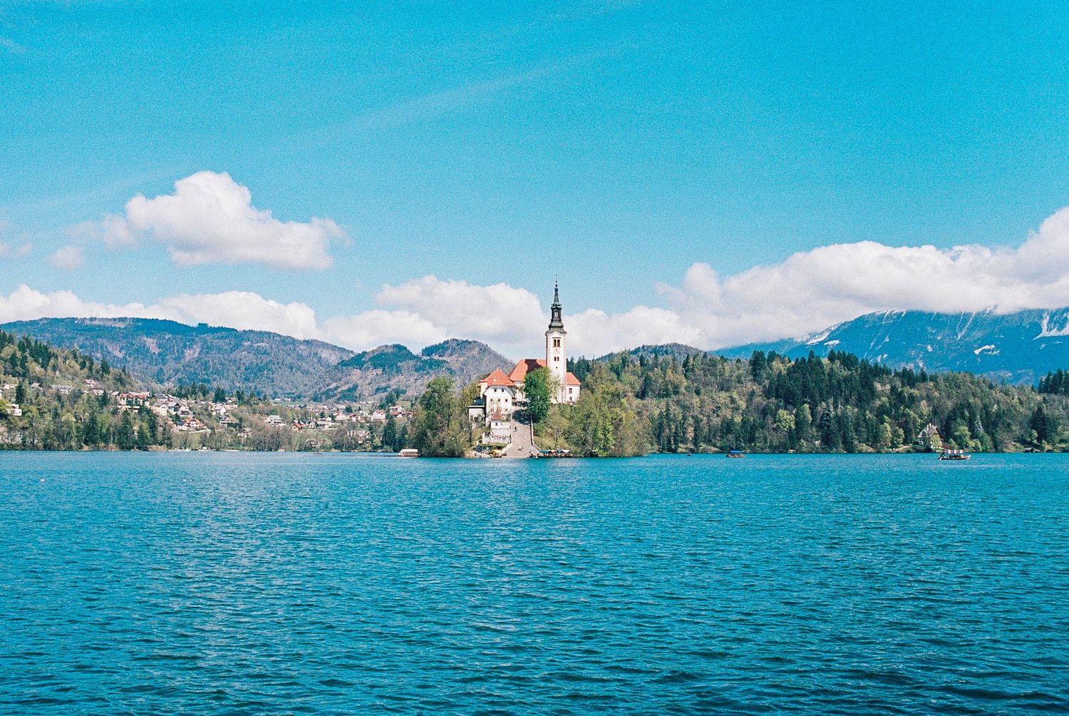 Lake Bled in Slovenia with iconic church on island and mountains in background under blue sky.