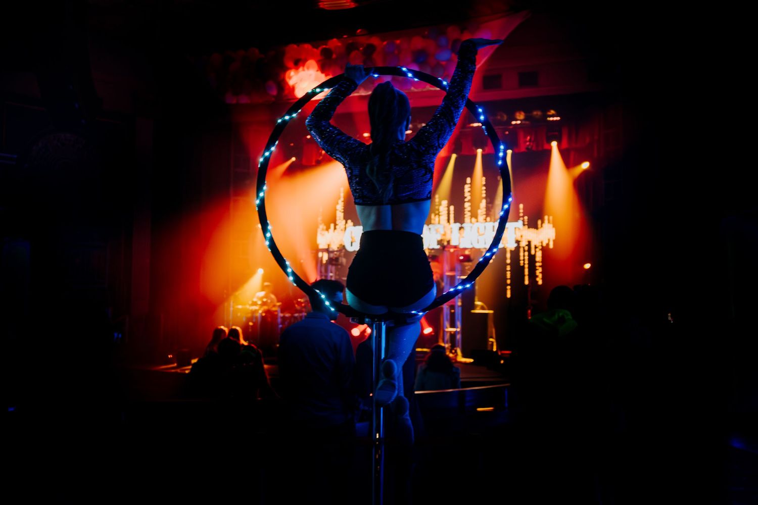 Illuminated blue heart-shaped stage prop against dark background with red lighting effects.