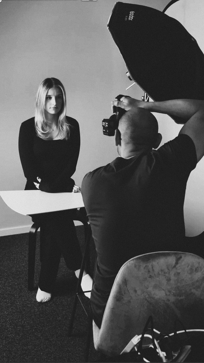 Fotograf tar porträttbild av kvinna i svart klädsel i studio. Fotograf Gabriel Alenius, Falun