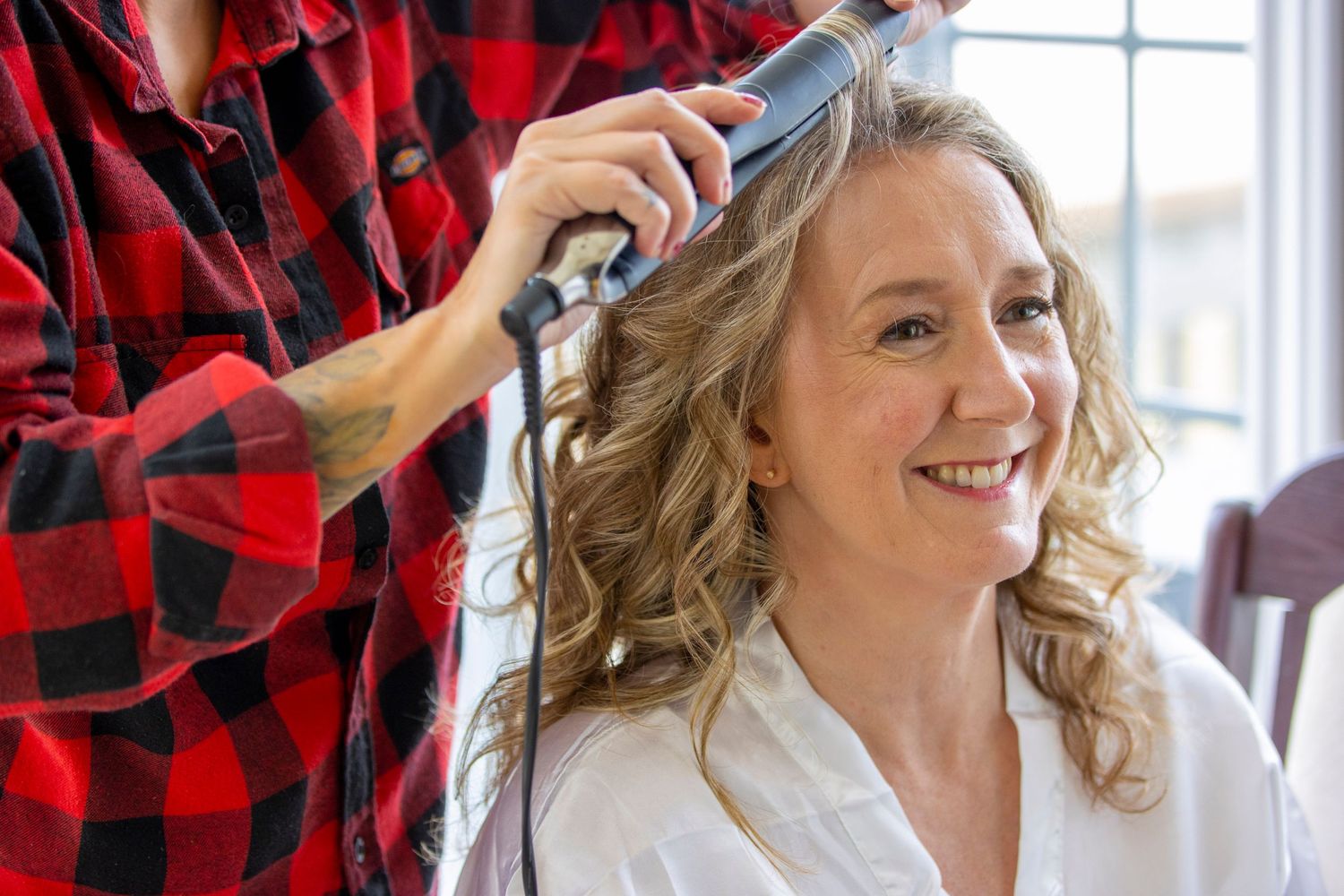 A hairstyling session during wedding preparations with soft natural lighting.