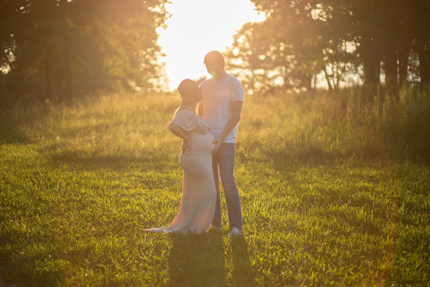 Golden sunset photoshoot in a grassy meadow with warm summer lighting.