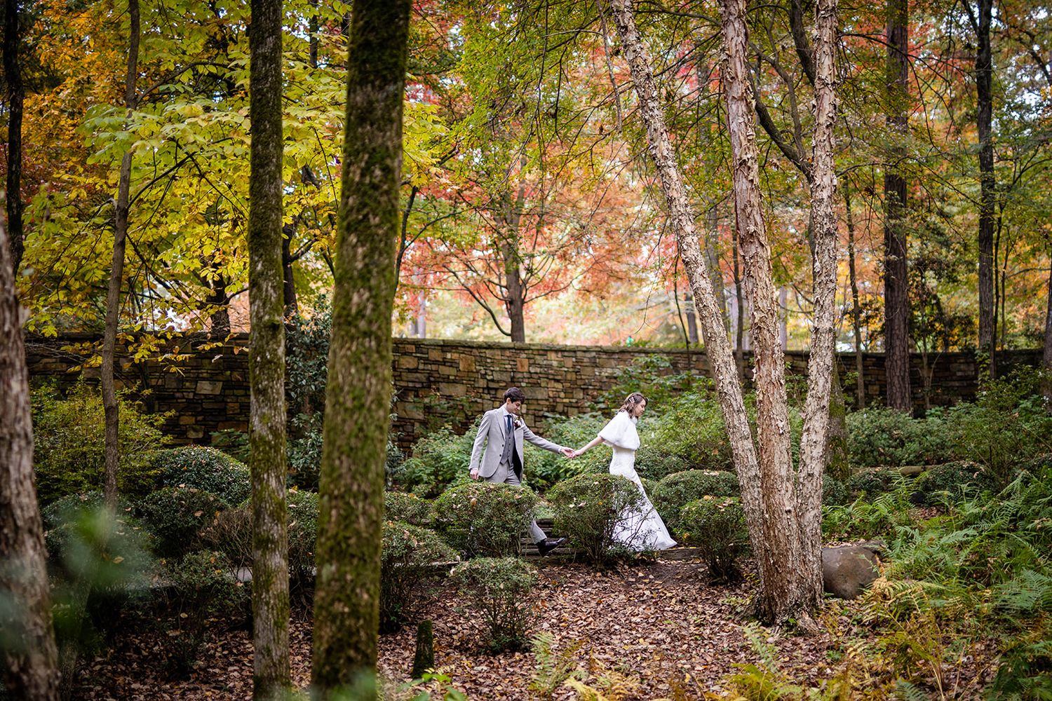 edding couple holding hands amidst autumn foliage in Hot Springs, captured by Michele McCoy Photography