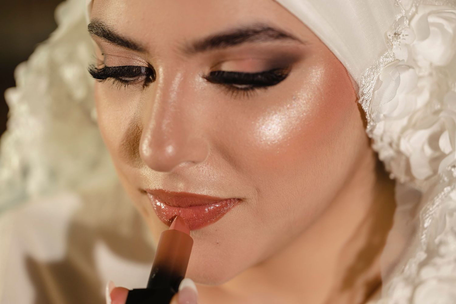 Close-up shot of bridal makeup application showing shimmering eyeshadow and lipstick.