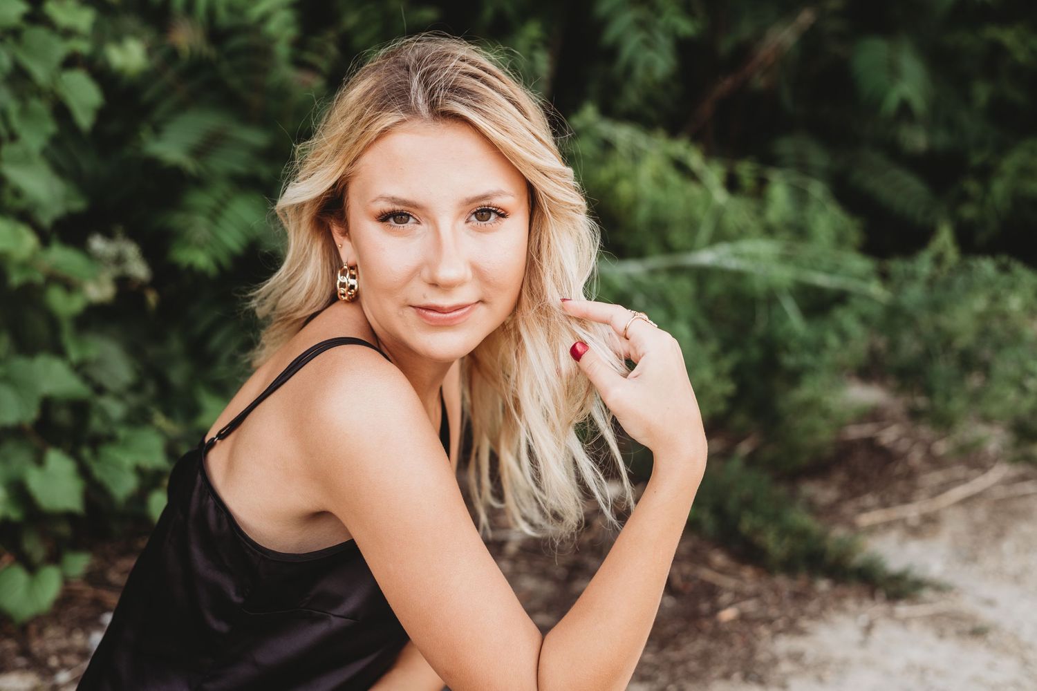Natural light portrait session in lush garden setting with green foliage.