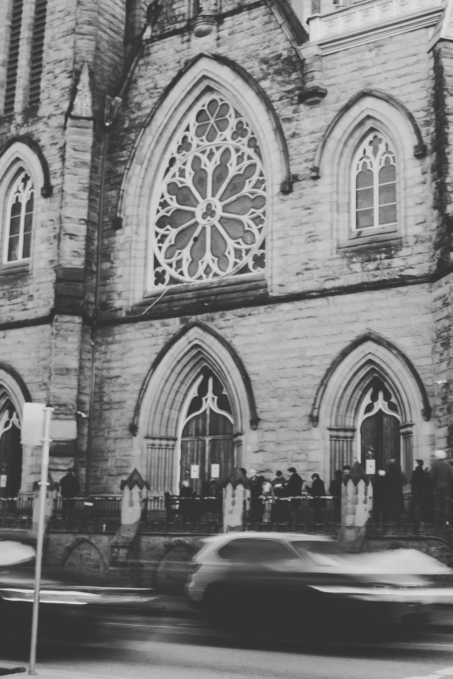 Gothic church exterior with ornate stone arches and rose windows captured in black and white.