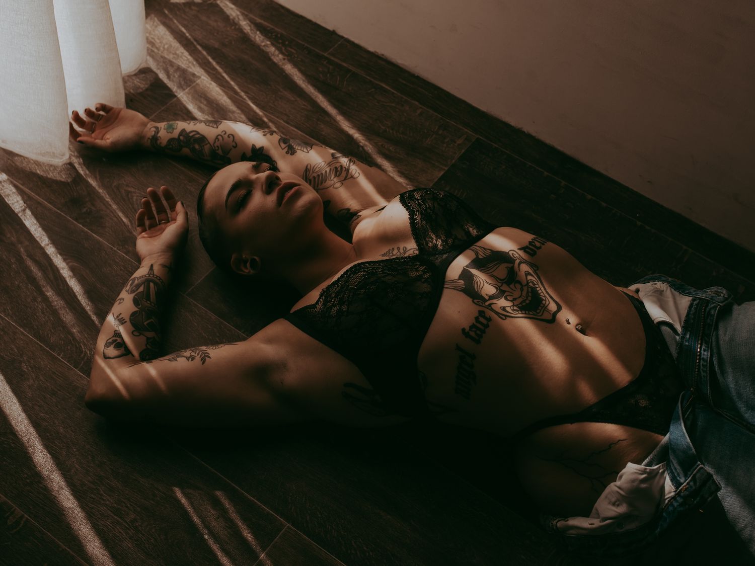 Artistic boudoir photo on wooden floor with dramatic shadows.