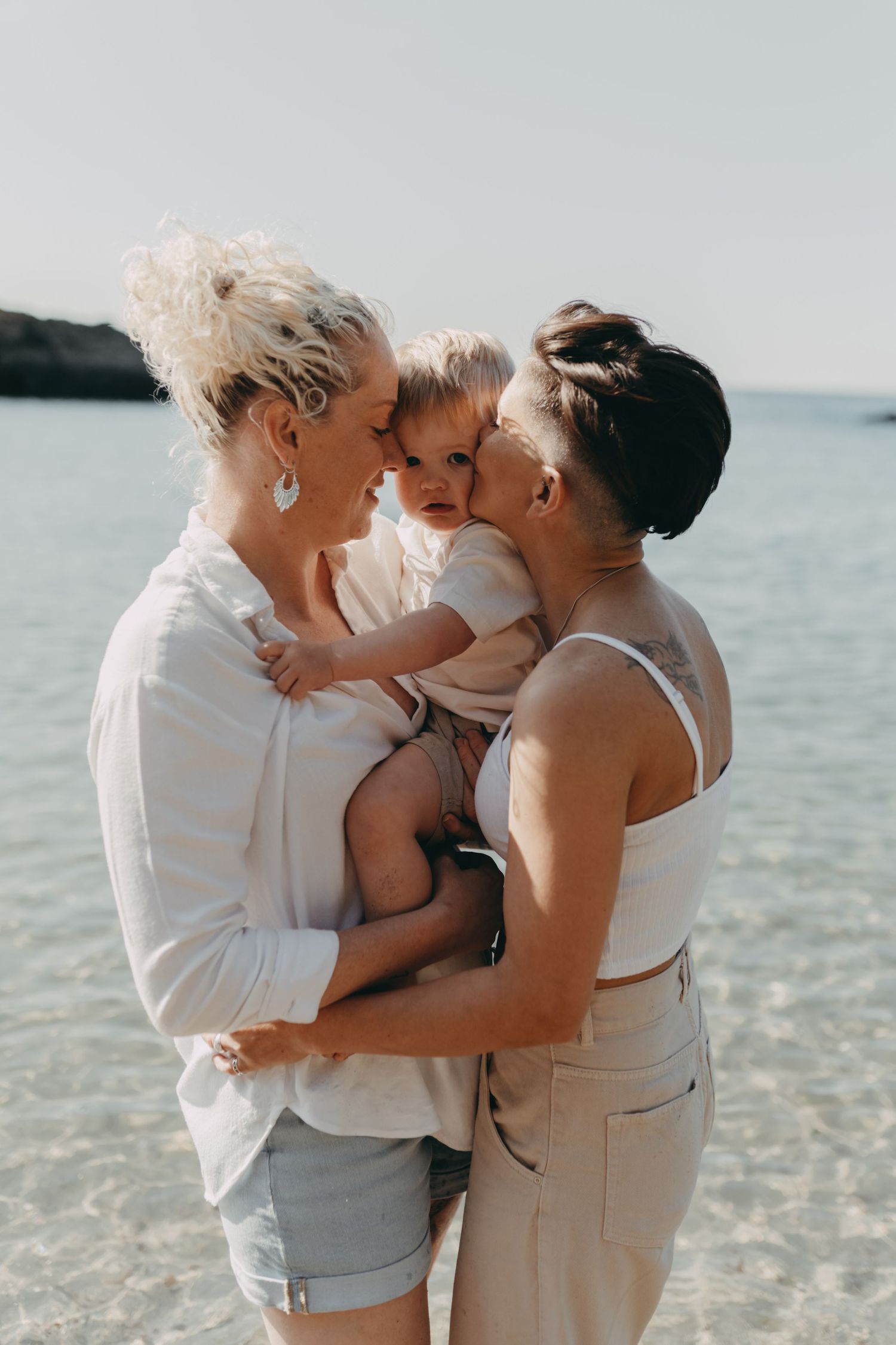 Intimate family portrait captured on a beautiful beach with crystal clear waters.