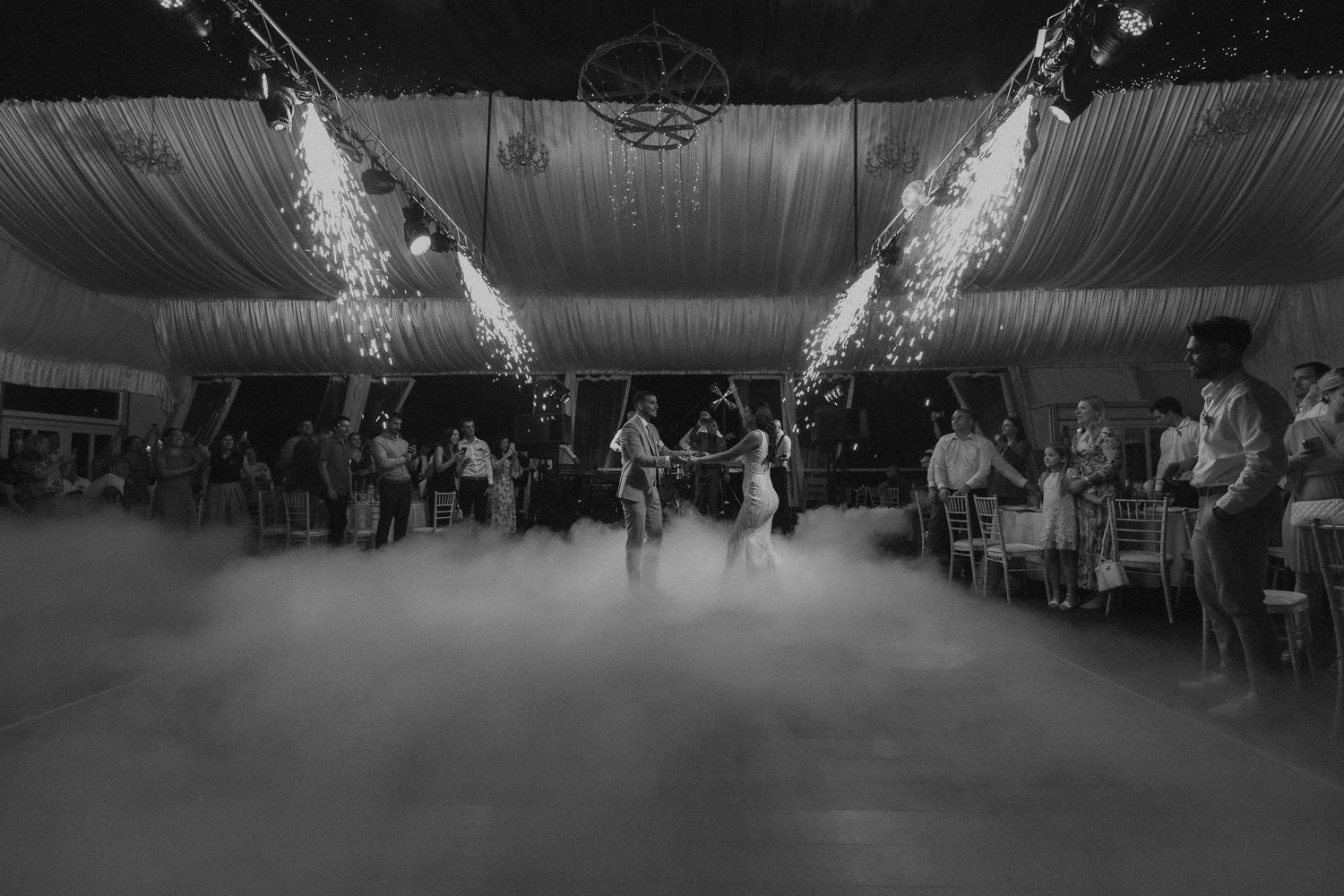 Fog and spotlights create dramatic atmosphere on wedding reception dance floor.