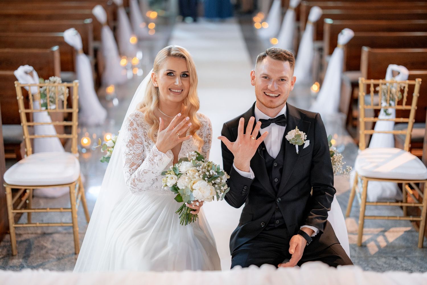 Wedding ceremony photo with decorated chairs and floral arrangements in a church aisle.