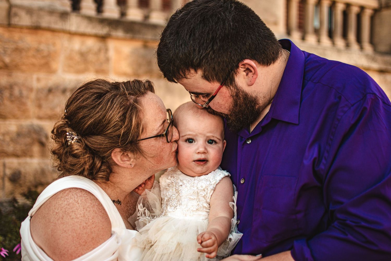 Family sharing tender moment together outdoors near historic stone building.