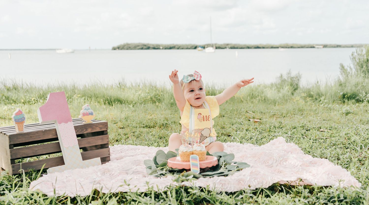 Outdoor Cake Smash Session at Maximo Park in St. Pete, FL; baby happy with cupcakes and birthday decorations