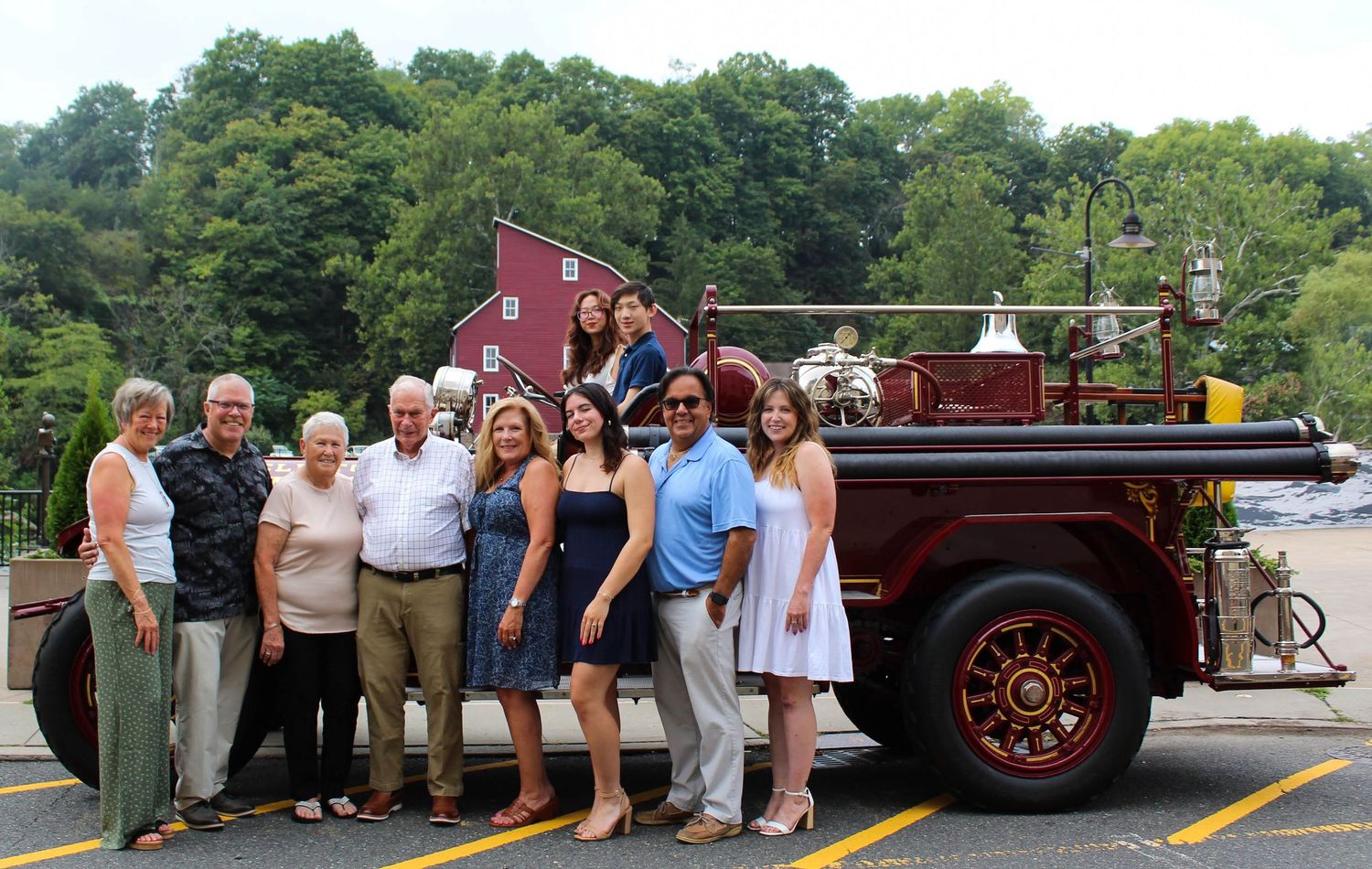 A group poses together in front of a vintage red fire truck at a community event.